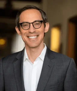 Smiling Glendale motorcycle accident lawyer in a suit standing in a professional office