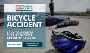 Injured cyclist lying on the road with helmet in foreground and text promoting Santa Clarita bicycle accident lawyer Law Offices of Adrianos Facchetti.