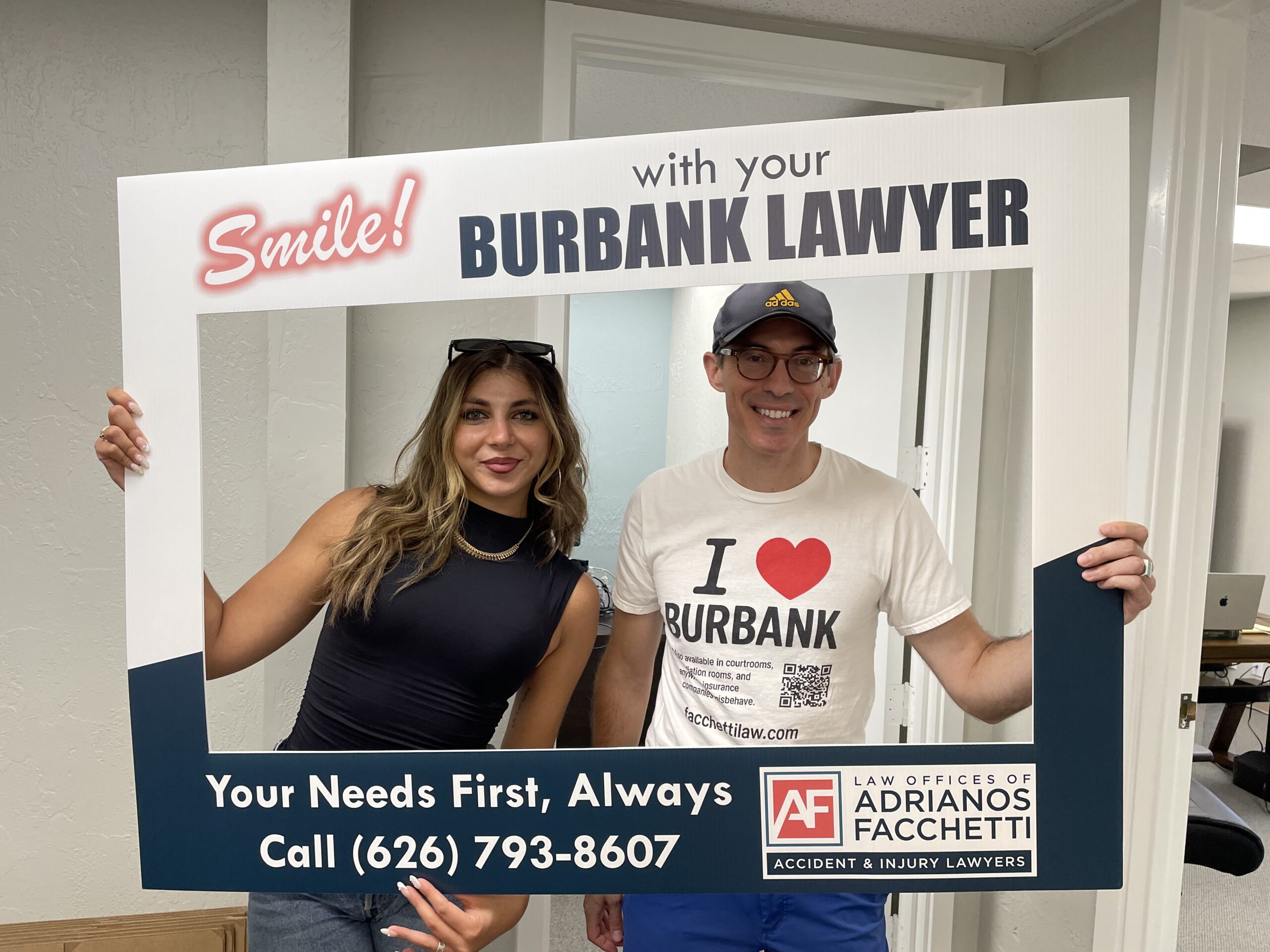 Burbank car accident lawyer Adrianos Facchetti with a team member holding a “Burbank Lawyer” frame at the Law Offices of Adrianos Facchetti.